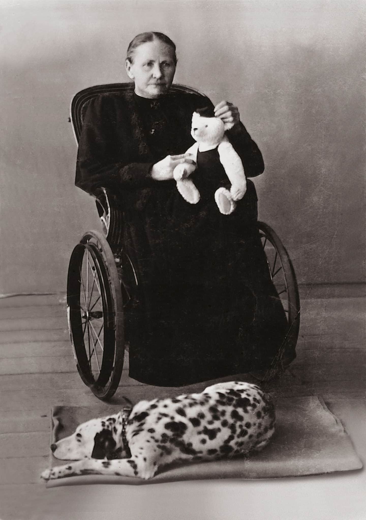 Historisches Porträt von Margarete Steiff im Rollstuhl, mit Stofftier und Dalmatiner, als Beispiel einer Unternehmerin mit Behinderung.